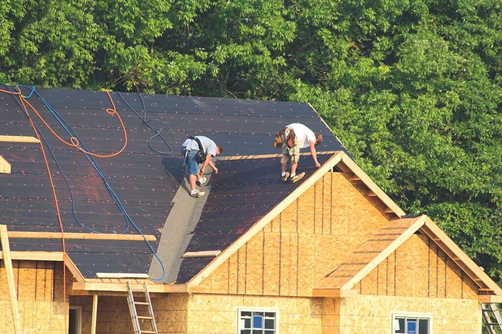 Homeowner examines loose shingles and water stains in an attic after a severe storm.