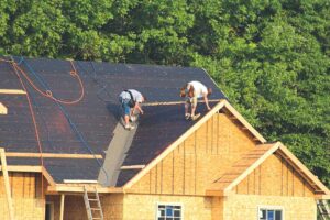 Homeowner examines loose shingles and water stains in an attic after a severe storm.